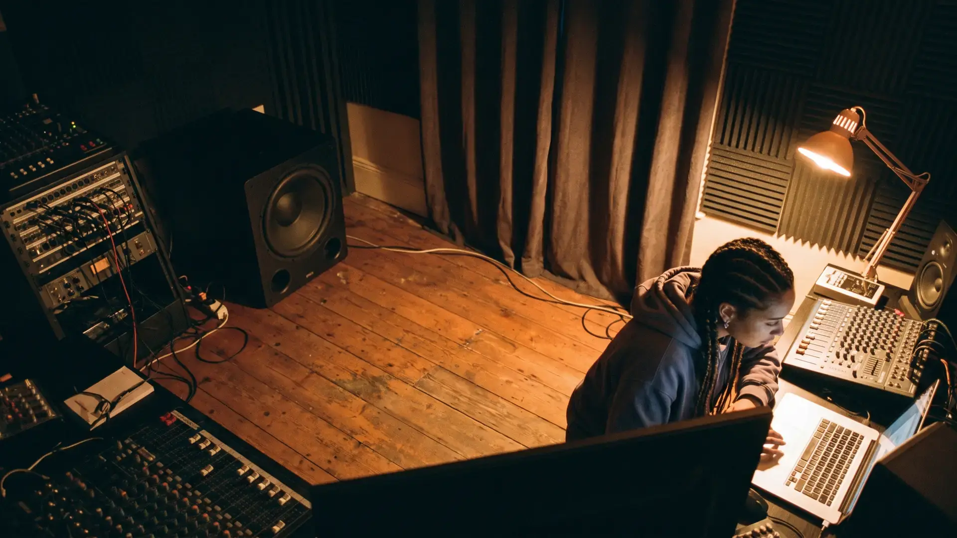 A producer at a home studio with a subwoofer on the floor and a treated corner: the dubstep label directory